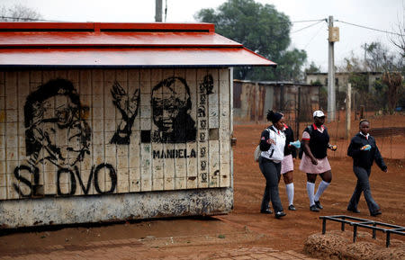 Schoolchildren walk next to murals of Nelson Mandela and Joe Slovo as they return from school at Slovo Park, an informal settlement located next to the Nancefield industrial area, south of Johannesburg, South Africa May 29, 2018. Picture taken May 29, 2018. REUTERS/Siphiwe Sibeko