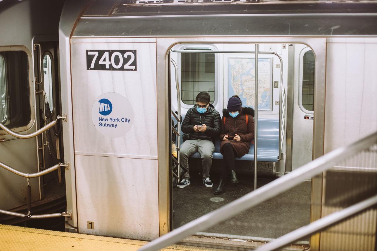 People in face masks are sitting in the train in the New York City Subway during Coronavirus outbreak