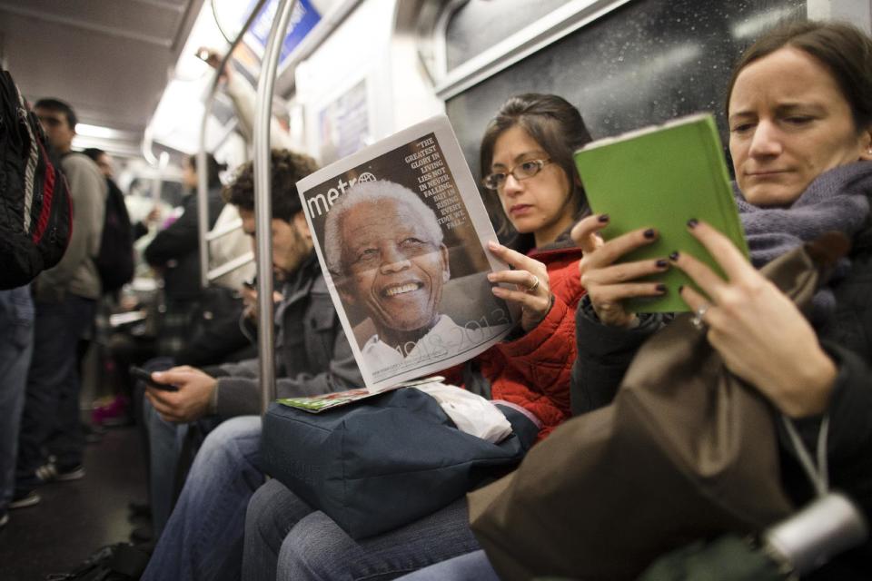 FILE - In this Dec. 6, 2013, file photo, a subway rider in New York reads a newspaper featuring news of the death of South African leader Nelson Mandela. Americans of all ages still pay heed to serious news even as they seek out the lighter stuff, choosing their own way across a media landscape that no longer relies on front pages and evening newscasts to dictate what's worth knowing, according to a new study from the Media Insight Project. (AP Photo/John Minchillo, File)