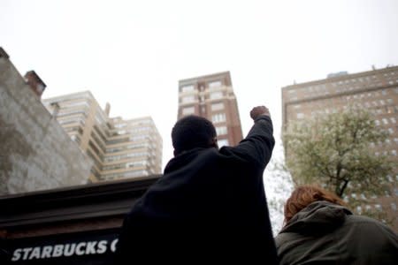A man raises his arm in protest outside the Center City Starbucks, where two black men were arrested, in Philadelphia, Pennsylvania U.S. April 16, 2018. REUTERS/Mark Makela