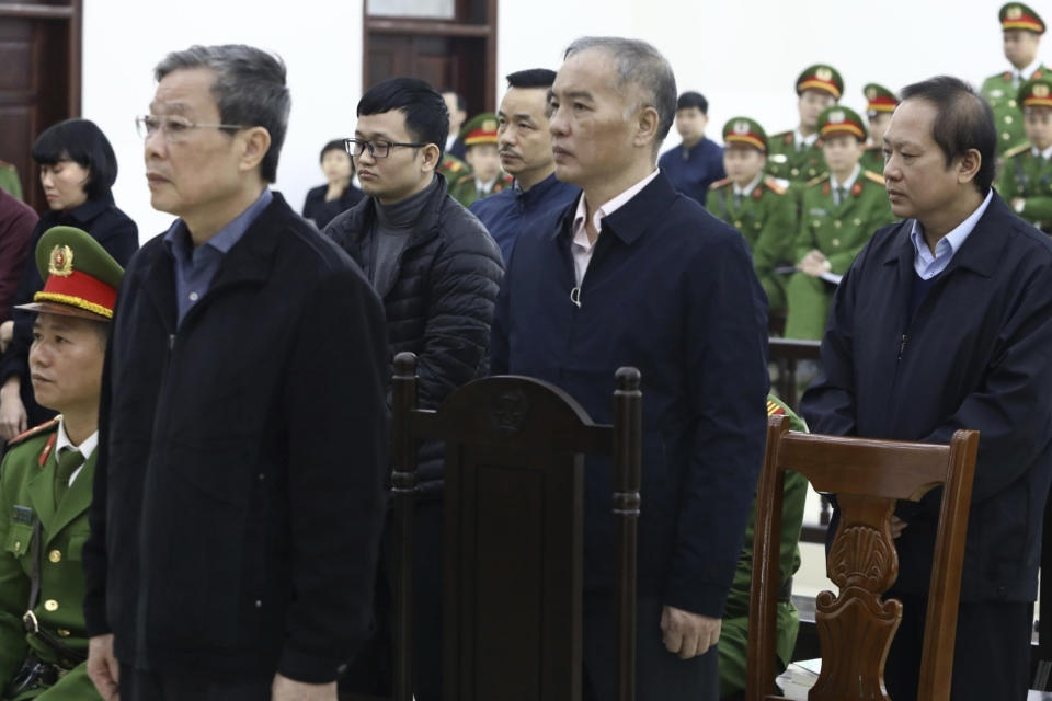 Vietnamese former Minister of information and communication Nguyen Bac Son, left, valuer Hoang Duy Quang, second left, former Mobifone Chairman Le Nam Tra, second right, former Minister of information and communication Truong Minh Tuan, right, stand as judge reads the verdicts at their trial in Hanoi, Vietnam Saturday, Dec. 28, 2019. Hanoi court on Saturday sentenced Son to life imprisonment in a multi-million dollar corruption case that also saw another minister and a dozen executives receive lengthy prison terms. (Nguyen Van Diep/VNA via AP)