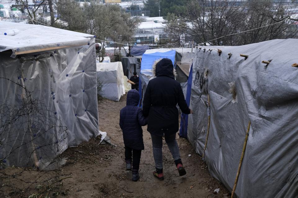 Migrants walk between makeshift tents outside the perimeter of the overcrowded Moria refugee camp after a rainfall on the northeastern Aegean island of Lesbos, Greece, Tuesday, Jan.28, 2020. Greece has been the first point of entry into the European Union for hundreds of thousands of people fleeing war or poverty at home, with most arriving on eastern Aegean islands from nearby Turkey. (AP Photo/Aggelos Barai)