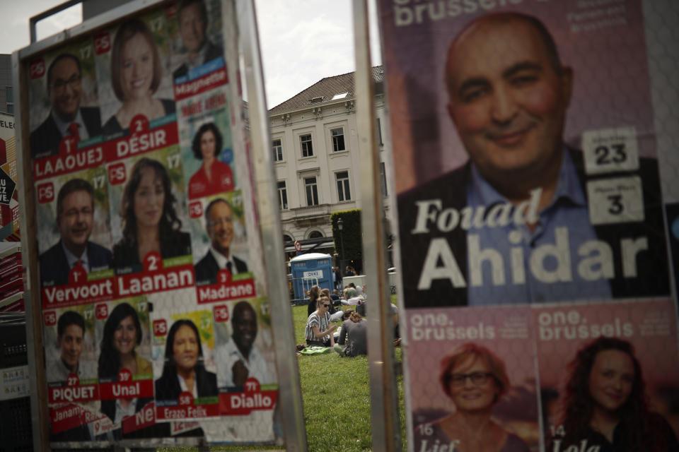 People sit on the grass near to political campaign posters near the European Parliament at the European quarter in Brussels, Thursday, May 23, 2019. Dutch and British voters were the first to have their say Thursday in elections for the European Parliament, starting four days of voting across the 28-nation bloc that pits supporters of deeper integration against populist euroskeptics who want more power for their national governments. (AP Photo/Francisco Seco)