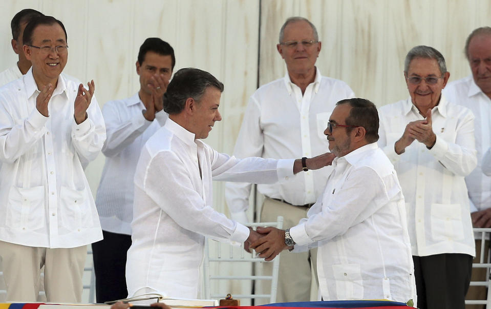 Aplaudidos por dignatarios visitantes, el presidente de Colombia Juan Manuel Santos (izq) saluda al comandate de las FARC Rodrigo Londoño, alias Timochenko, tras la firma de un acuerdo de paz el 26 de septiembre del 2016 en Cartagena. La implementación del acuerdo, no obstante, tropieza con obstáculos, incluidos los asesinatos de numerosos excombatientes rebeldes. (AP Photo/Fernando Vergara, File)