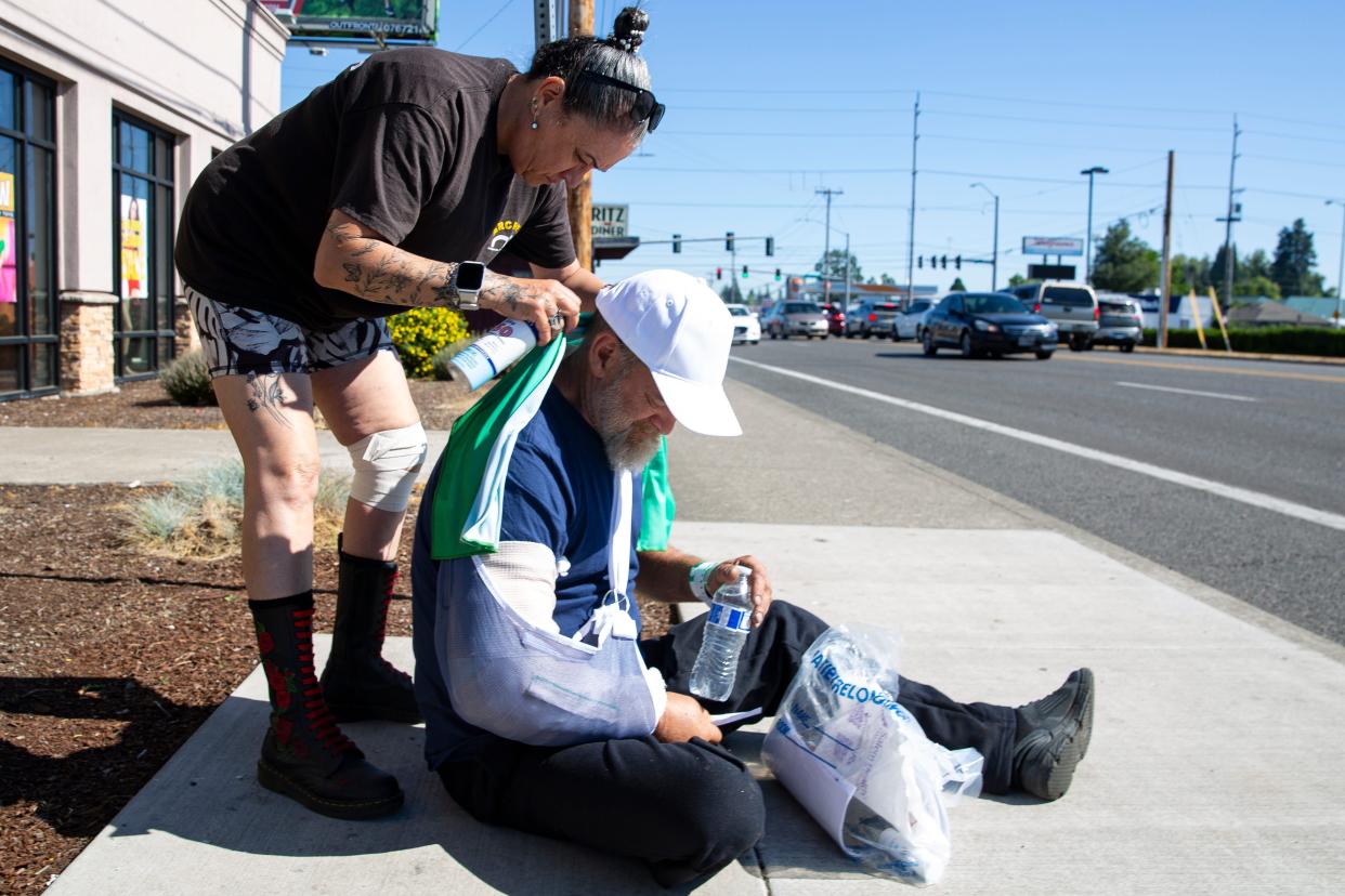 Maggy Johnston, an outreach coordinator with Mid-Willamette Valley Community Action Agency, wraps a cold towel around Michael Pesterfluid during the heat wave in Salem, Oregon, on July 5, 2024.
