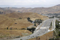 In this July 25, 2019, photo, U.S. Highway 101 passes between two separate open space preserves on conservancy lands in the Santa Monica Mountains in Agoura Hills, Calif. Hoping to fend off the extinction of mountain lions and other species that require room to roam, transportation officials and conservationists will build a mostly privately funded wildlife crossing over this freeway. It will give big cats, coyotes, deer, lizards, snakes and other creatures a safe route to open space and better access to food and potential mates. (AP Photo/Marcio Jose Sanchez)