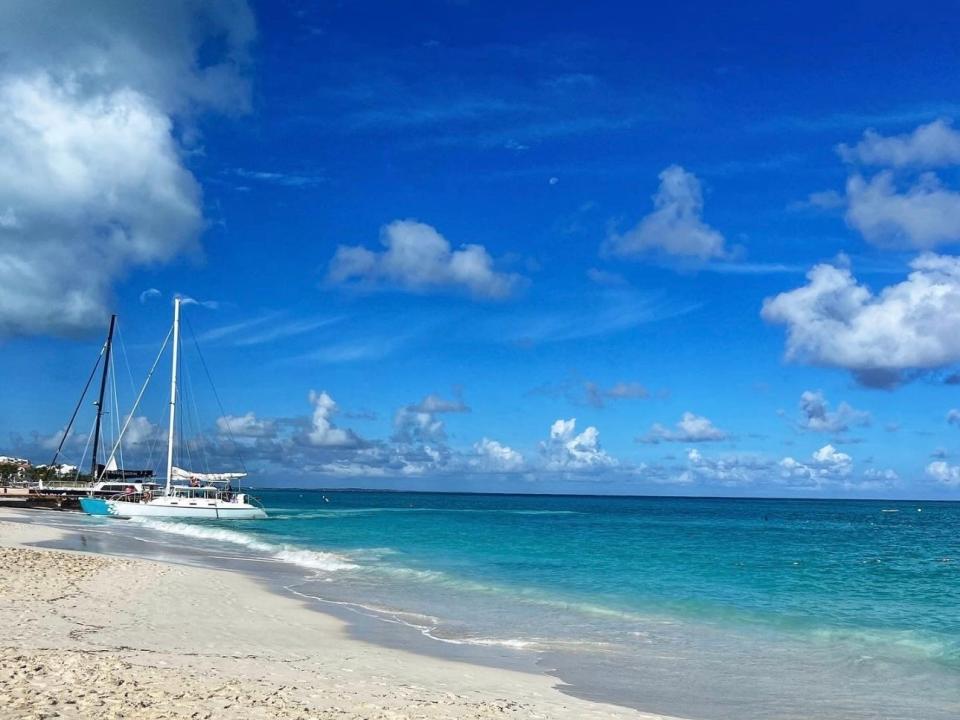 Two boats are docked on the coast of a beach with vibrant blue waters.