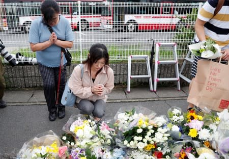 Women pray outside the Kyoto Animation building which was torched by arson attack, in Kyoto