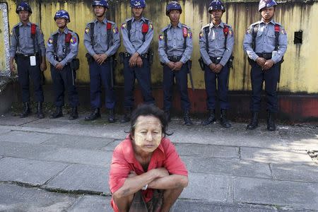 Policemen secure the road as a man waits to try to get a glimpse of U.S. President Barack Obama's convoy passing near the house of opposition politician Aung San Suu Kyi,in Yangon November 14, 2014. REUTERS/Minzayar