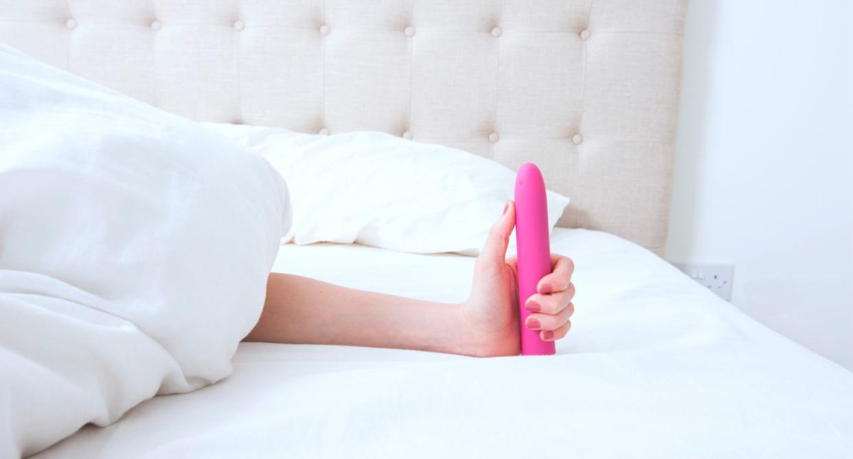 Woman holding pink vibrator in bed. (Getty Images)