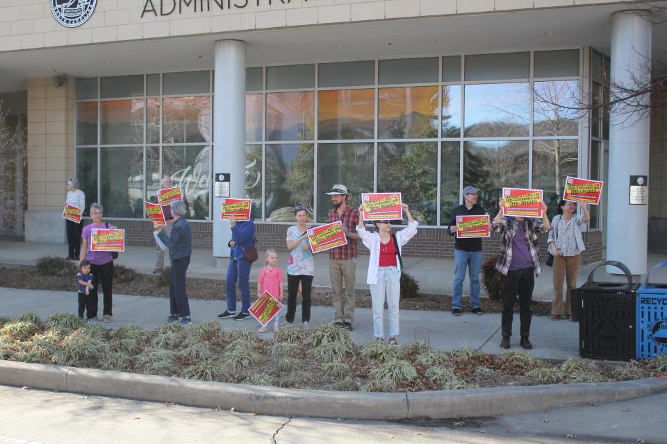 A group of people held signs outside prior to the March 7 Buncombe County Board of Commissioners meeting asking for the Swannanoa Library to remain open.