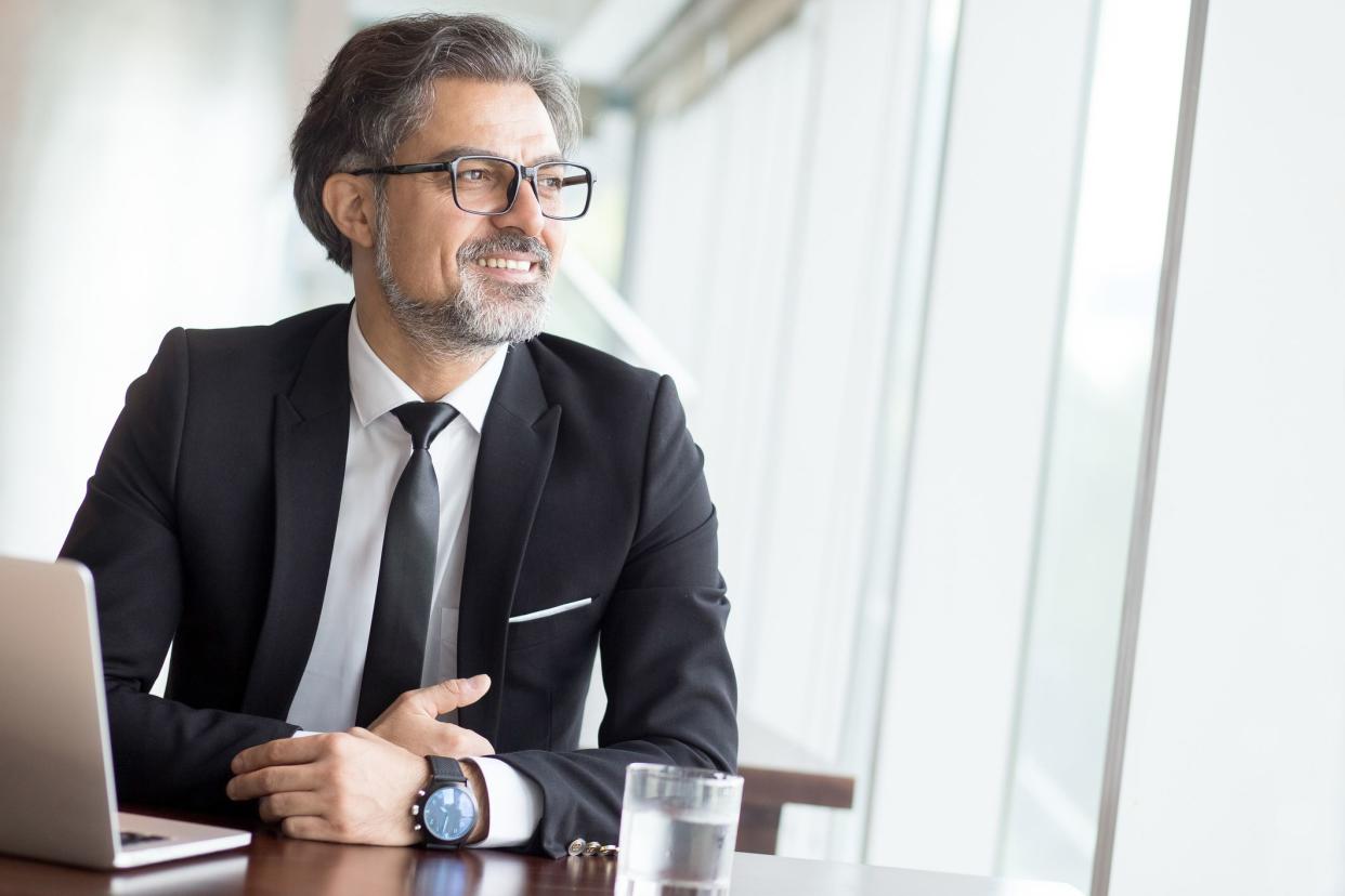 middle-aged man smiling looking out window at office