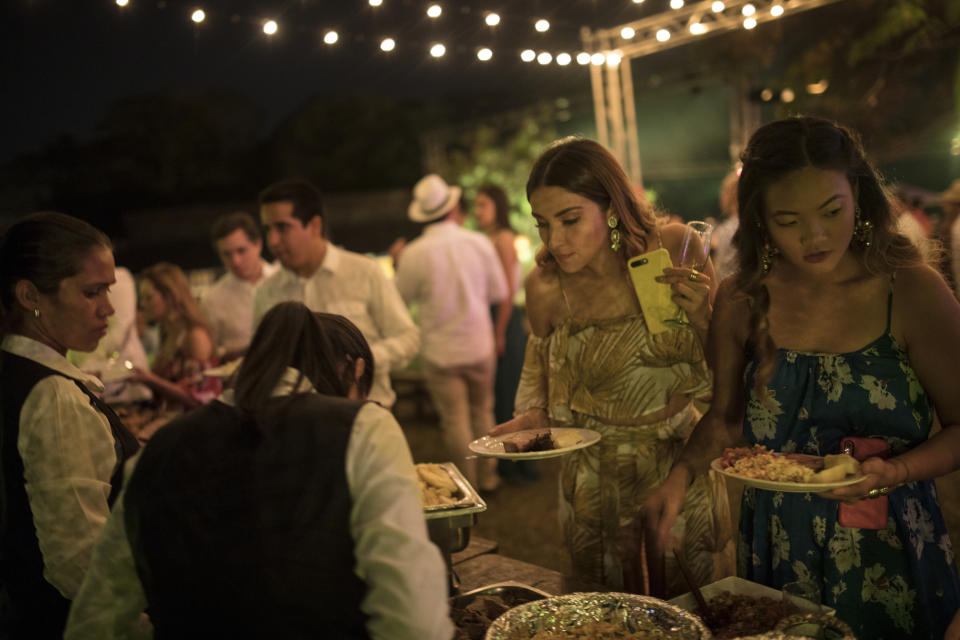 Huéspedes de la boda de María Fernanda Vera y Juan José Pocaterra se sirven comida en la Hacienda Camburito de Acarigua, Venezuela, el 16 de febrero del 2019. (AP Photo/Rodrigo Abd)