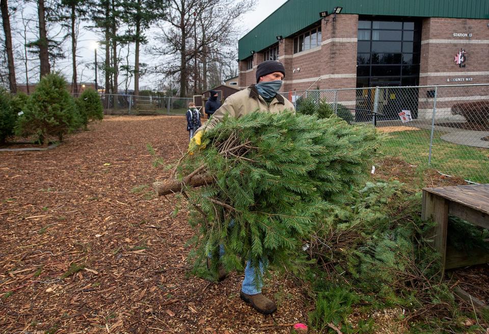 Firefighter Andrew Korhonen helps out in the selling of Christmas trees at the Levittown Fire. Co. No.2 in Levittown, on Wednesday, Dec. 9, 2020.