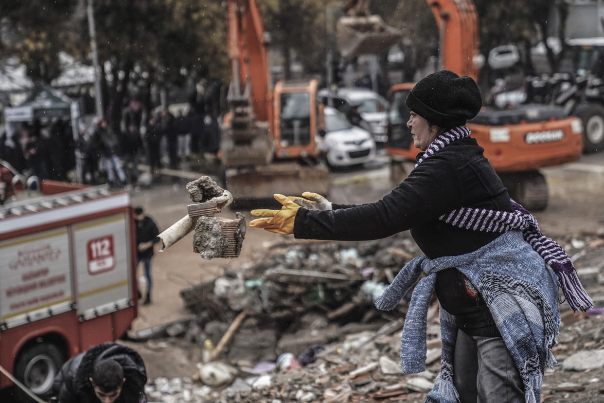 A woman removes debris from a destroyed building as she searches for people with emergency teams in Gaziantep, Turkey, Monday, Feb. 6, 2023. A powerful quake has knocked down multiple buildings in southeast Turkey and Syria and many casualties are feared. (AP Photo/Mustafa Karali)