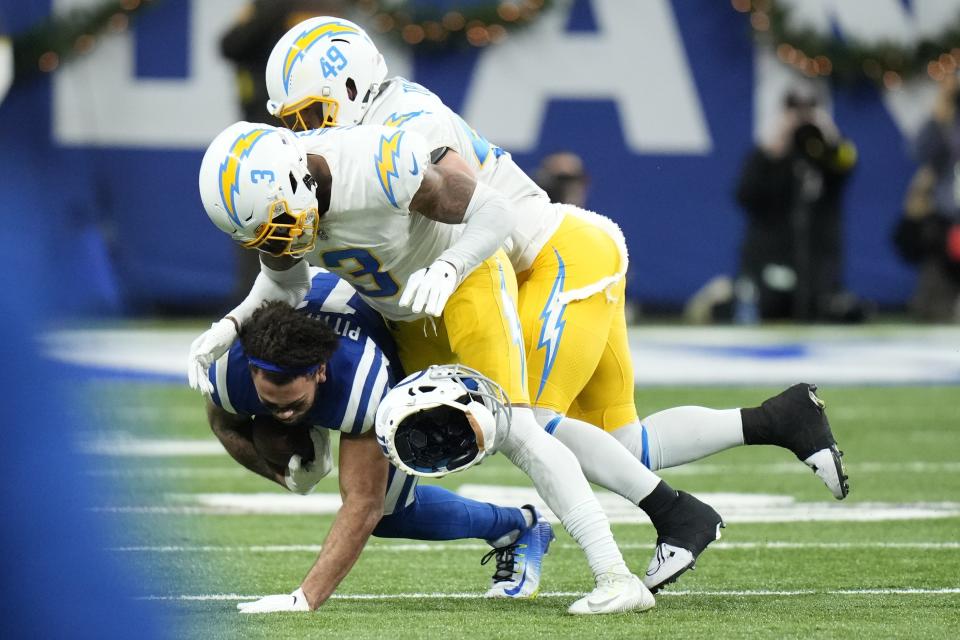 Indianapolis Colts' Michael Pittman Jr. (11) helmet comes off as he is tackled by Los Angeles Chargers' Derwin James Jr. (3) and Drue Tranquill (49) during the first half of an NFL football game, Monday, Dec. 26, 2022, in Indianapolis. (AP Photo/AJ Mast)