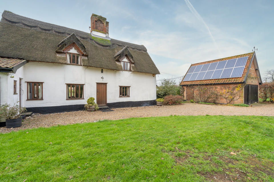 Solar panels on a garage roof provide electricity for this 17th century thatched cottage. 