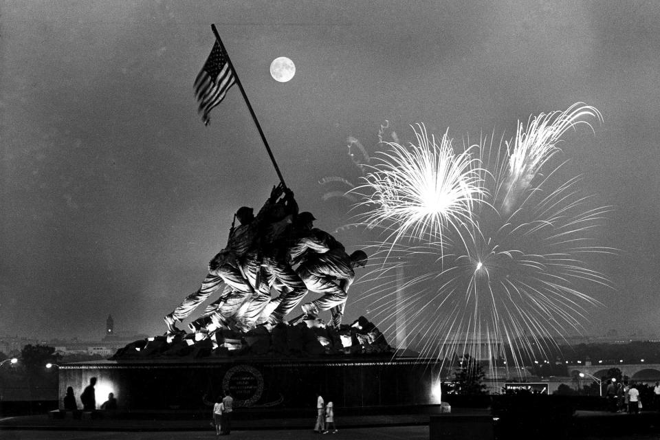 FILE - In this July 4, 1966 file photo, the moon shines above the United States Marine Corps War Memorial, which depicts a scene from Iwo Jima, as fireworks burst over Washington, seen from the Virginia side of the Potomac River. The Washington Monument and the Lincoln Memorial are seen in the background. (AP Photo/Charles Tasnadi, File)