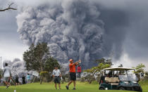 <p>People play golf as an ash plume rises in the distance from the Kilauea volcano on Hawaii’s Big Island on May 15, 2018 in Hawaii Volcanoes National Park, Hawaii. (Photo: Mario Tama/Getty Images) </p>