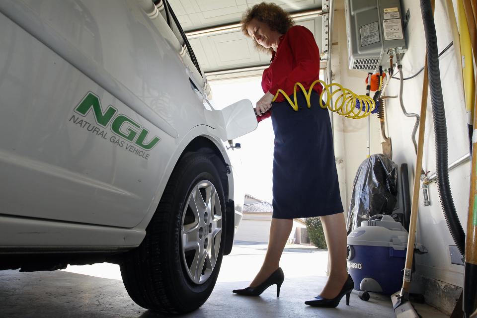 Connie Jones connects the nozzle of a home refueling station to her 2003 natural gas powered Honda Civic in the garage of her home in Chandler, Arizona, October 3, 2013. (REUTERS/Ralph D. Freso)