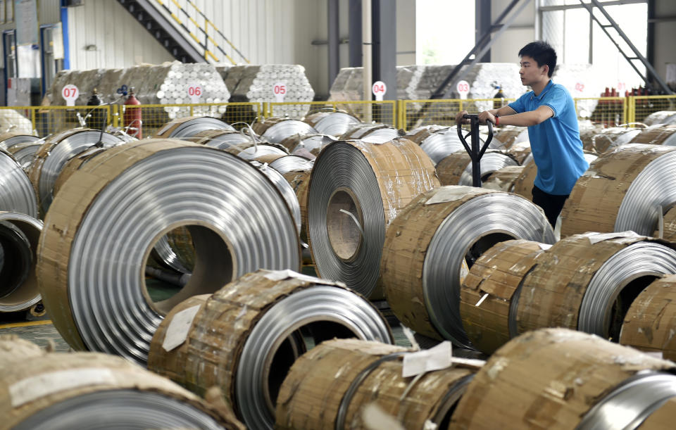 In this Wednesday, May 15, 2019, photo, a worker moves aluminum pipes in a factory in Zouping in eastern China's Shandong province. Figures released on Wednesday showed China's factory output and consumer spending weakened in April as a tariff war with Washington intensified, adding to pressure on Beijing to shore up shaky economic growth. (Chinatopix via AP)