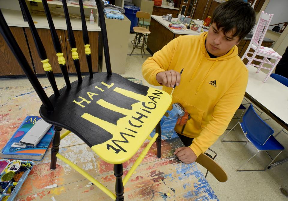 Jefferson High School junior Joseph Drew paints his University of Michigan-themed chair which will be auctioned off for this year's Relay for Life Monroe.