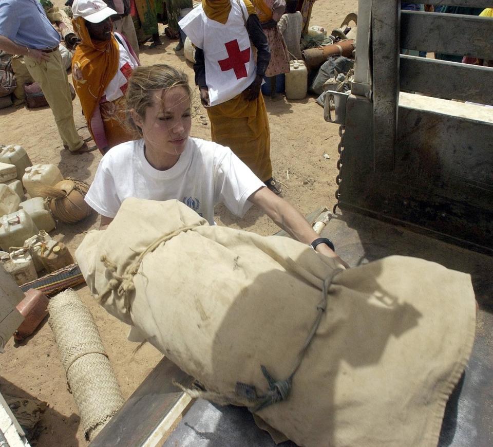 Jolie helps Sudanese refugees load their belongings onto a truck near Tine, Chad, June 4, 2004.