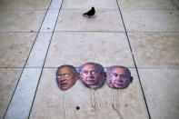 Masks depicting Israeli Prime Minister Benjamin Netanyahu and Israeli Defense Minister Benny Gantz lay on the ground during a protest against a parliamentary vote to dissolve the Knesset and send the country to its fourth elections in two years while it still hasn't approved a national budget for 2020, in Tel Aviv, Wednesday, Dec. 2, 2020. (AP Photo/Oded Balilty)