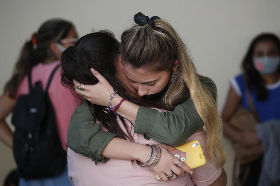 Amigas de Úrsula Bahillo, de 18 años y que fue encontrada en un campo apuñalada hasta la muerte el lunes, se abrazan durante su velorio en Rojas, Argentina, el miércoles 10 de febrero de 2021. El exnovio de Bahillo, un oficial de policía, ha sido arrestado en relación con su muerte. (AP Foto/Natacha Pisarenko)