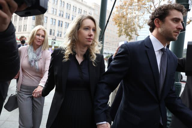 <p>Justin Sullivan/Getty</p> Elizabeth Holmes arrives at federal court with her partner Billy Evans and mother Noel Holmes on November 18, 2022.
