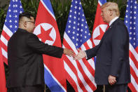 FILE - U.S. President Donald Trump, right, reaches to shake hands with North Korea leader Kim Jong Un at the Capella resort on Sentosa Island in Singapore on June 12, 2018. Since assuming power 10 years ago, North Korean leader Kim Jong Un has ruled the isolated country with absolute power, significantly expanded its nuclear arsenal and become the North’s first ruler to hold a summit with a sitting U.S. president. But now, he’s hunkering down and struggling to revive a dilapidated economy battered hard by pandemic-related border shutdowns, toughened U.N. sanctions and mismanagement. (AP Photo/Evan Vucci, File)