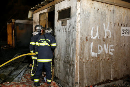 Firefighters extinguish shelters during a fire which destroyed many wood houses at a camp for migrants in Grande-Synthe, France, April 11, 2017. REUTERS/Pascal Rossignol