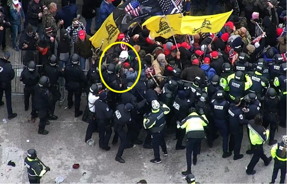 Law enforcement reviewed CCTV from the Capitol grounds showing footage of the West Plaza area taken at or around 2:13 PM. The CCTV captured the incident in Exhibit 5 from another angle and shows GIETZEN, in the white helmet and a green jacket, in an altercation with law enforcement when he thrusts his fist towards officers’ shields.