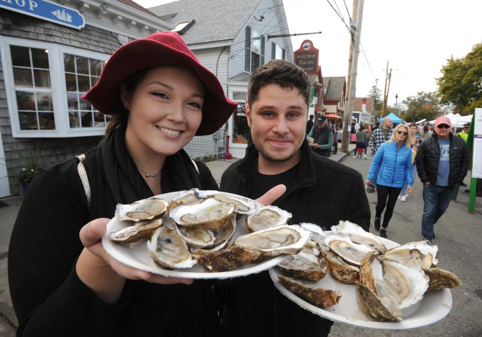 Lisa Laney, of Pennsylvania, left, and Adam Pummill, of Maryland, hold up their plates of oysters during the 19th Wellfleet OysterFest on Oct. 20, 2019. Proceeds from this year's event, Oct. 14 and 15, support Wellfeet SPAT's (Shellfish Promotion and Tasting Inc.) education mission that includes a college scholarship program and community grants.