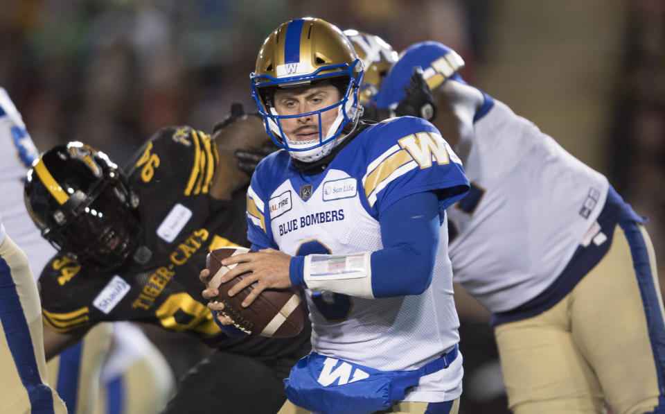 Winnipeg Blue Bombers quarterback Zach Collaros avoids a tackle from Hamilton Tiger-Cats' Lorenzo Mauldin during the first half of a CFL football game in the 107th Grey Cup in Calgary, Alberta, Sunday, Nov. 24, 2019. (Nathan Denette/The Canadian Press via AP)