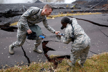 Senior Airman John Linzmeier and Technical Sergeant Alison Bruce-Maldonado of the Hawaii National Guard document road damage in Leilani Estates during ongoing eruptions of the Kilauea Volcano in Hawaii, U.S., May 18, 2018. REUTERS/Terray Sylvester