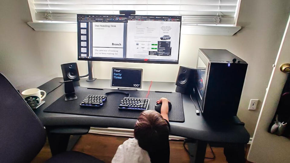 A toddler playing with a trackball mouse on a standing desk