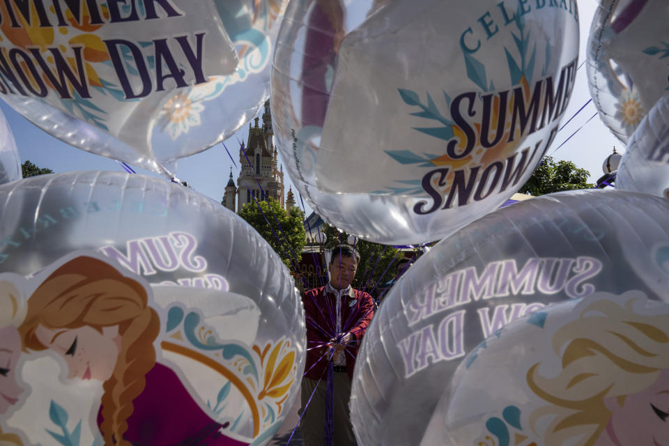 An employee holds Frozen themed balloons outside the World of Frozen themed area prior to its opening ceremony at Disneyland Resort in Hong Kong, Monday, Nov. 20, 2023. (AP Photo/Louise Delmotte)