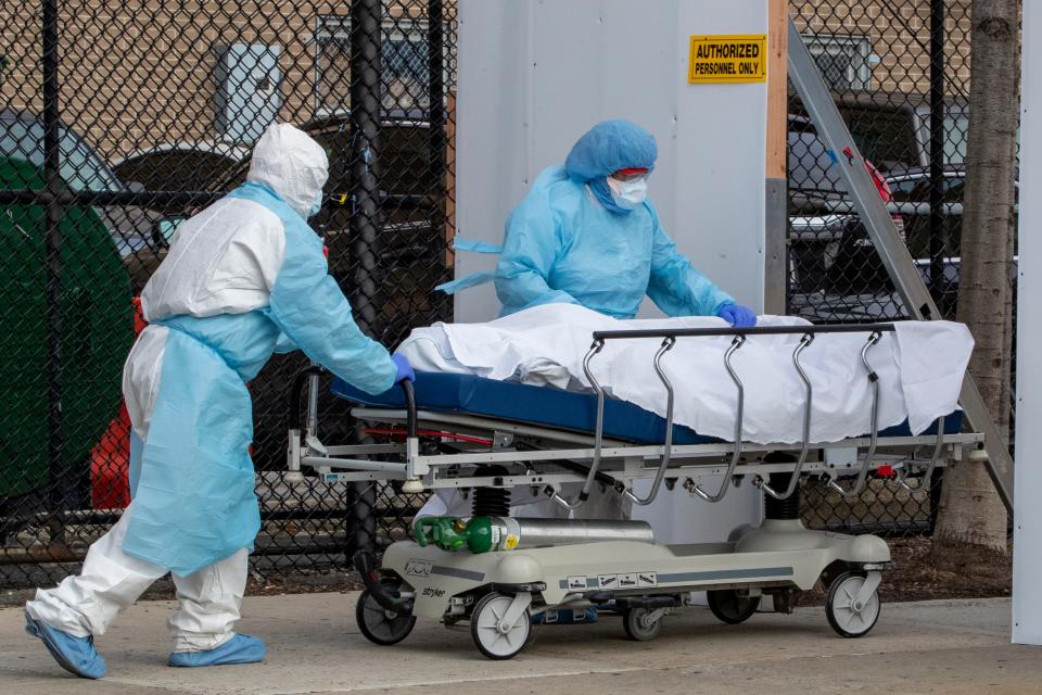 Medical personnel wearing personal protective equipment remove a body from the Wyckoff Heights Medical Center to refrigerated containers parked outside April 2 in the Brooklyn borough of New York.