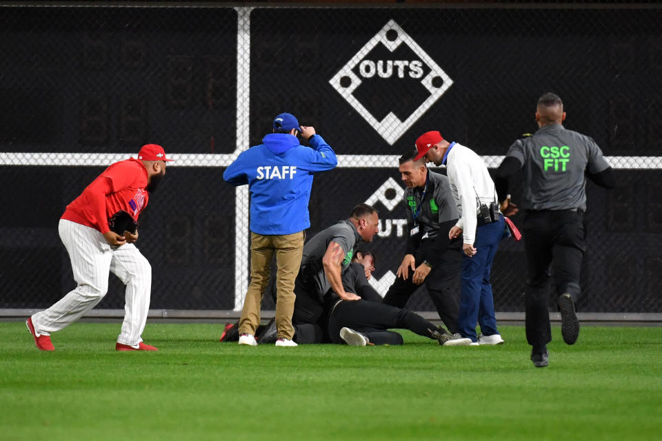 Oct 17, 2023; Philadelphia, Pennsylvania, USA; Security members tackle a fan after running onto the field after the ninth inning for game two of the NLCS for the 2023 MLB playoffs against the Arizona Diamondbacks at Citizens Bank Park. Mandatory Credit: Eric Hartline-USA TODAY Sports