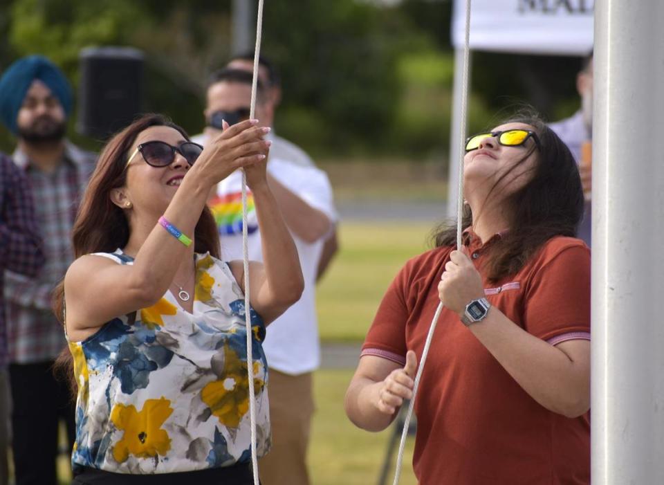 Destiny Rodríguez, integrante de la junta del Distrito de  Universidades Comunitarias del Centro del Estado, a la izquierda, y Mia Aguilar, presidenta del cuerpo estudiantil del Madera Community College, a la derecha, izaron la bandera del Orgullo en el campus el lunes 3 de junio de 2024.