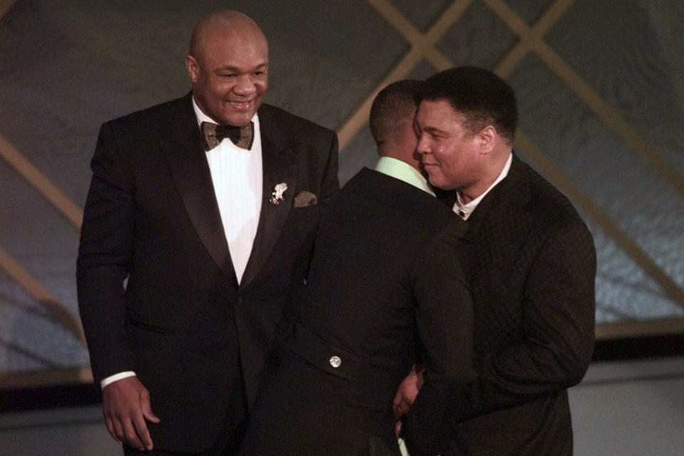 FILE - In this March 24, 1997, file photo, George Foreman, left, looks on as Will Smith, center, gives Muhammad Ali a hug after Ali And Foreman made an appearance on stage after the film "When We Were Kings" was awarded Best Documentary Feature at the 69th Annual Academy Awards in Los Angeles. The Associated Press has compiled a list of the best sports movies ever made — a one-of-a-kind AP Top 25. Two documentaries made the rankings: “Hoop Dreams” at No. 14 and “When We Were Kings,” tied for No. 21. (AP Photo/Susan Sterner, File)