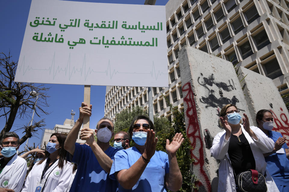 A nurse holds an Arabic placard that reads: "Monetary policy that stifles hospitals is a failure," as he protests with other medical workers and doctors the deteriorating economic conditions, outside the Central Bank, in Beirut, Lebanon, Thursday, May 26, 2022. The syndicates of doctors in Beirut and the North as well as the Syndicate of Private Hospital Owners declared a two-day general strike Thursday and Friday. (AP Photo/Hussein Malla)