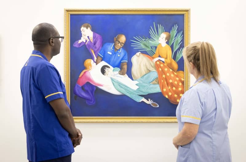 Senior nurse, Isaac Otengo and healthcare assistant Wendy Phillips look at a reimagined version of Nils Dardel's 'The Dying Dandy' by Lisa Buchanan, commissioned by end-of-life charity Marie Curie to support its flagship fundraiser, the Great Daffodil Appeal, at the Great Daffodil Appeal, a Mayfair Gallery at 56 Conduit Street in London. Matt Crossick/PA Wire/dpa