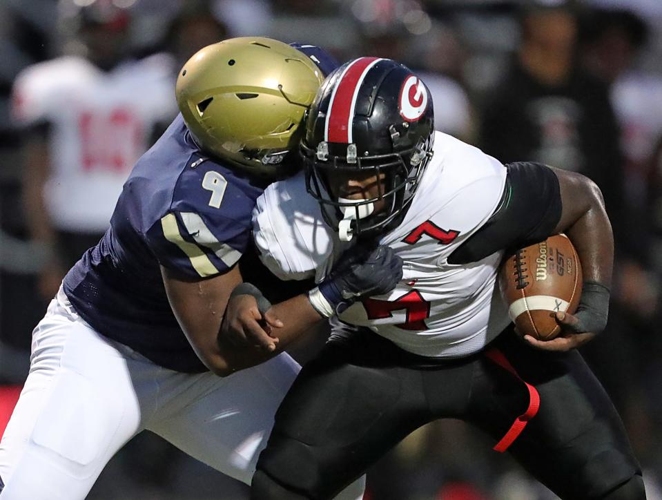 Hoban defensive end Jordan Pritchard-Sewell, left, brings down Glenville running back D'Shawntae Jones on Oct. 6 in Akron.