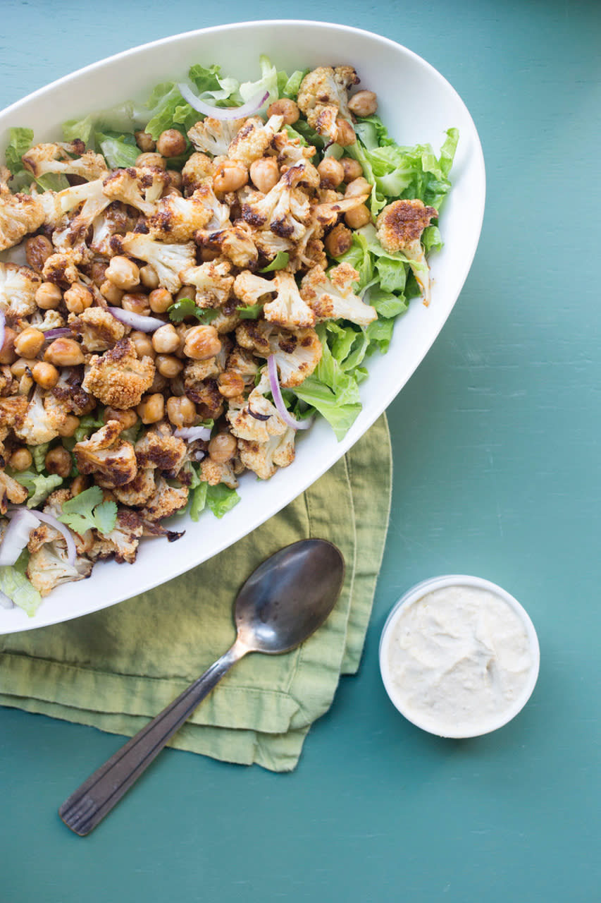 This November 2017 photo shows a roasted cauliflower and chickpea salad with garlic-tahini dressing on the side in New York. This dish is from a recipe by Katie Workman. (Lucy Beni via AP)