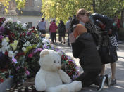 A woman prays near a memorial to the people killed during an attack in the vocational college in Kerch, Crimea, Thursday, Oct. 18, 2018. An official says that authorities on the Crimean Peninsula are searching for a possible accomplice of the student who carried out an attack on a vocational school, killing 20 people and wounding more than 50 others. (AP Photo/Str)