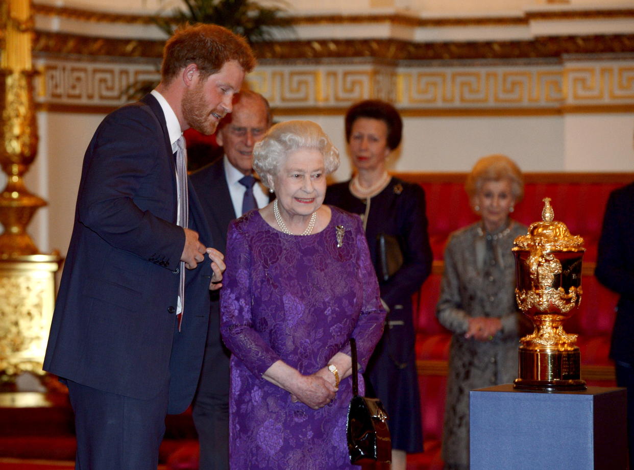 Britain's Prince Harry (L) and Queen Elizabeth look at the Webb Ellis Cup on a plinth during a Rugby World Cup reception at Buckingham Palace, London October 12, 2015.  REUTERS/Anthony Devlin/Pool      TPX IMAGES OF THE DAY     