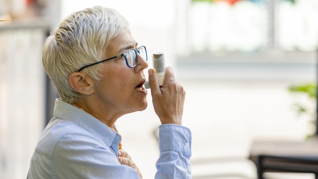 mature business woman using asthma inhaler