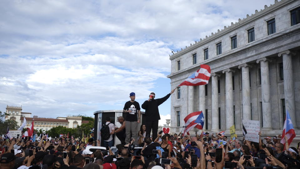 Puerto Rican rapper Rene Juan Perez known by his stage name Residente and Benito Antonio Martinez Ocasio, known by his stage name Bad Bunny, warm up the crowd in front of the Puerto Rican Capitol, before a protest march against governor Ricardo Rosello, in San Juan, Puerto Rico, Wednesday, July 17, 2019. Protesters are demanding Rosselló step down for his involvement in a private chat in which he used profanities to describe an ex-New York City councilwoman and a federal control board overseeing the island's finance. (AP Photo/Dennis M. Rivera Pichardo)